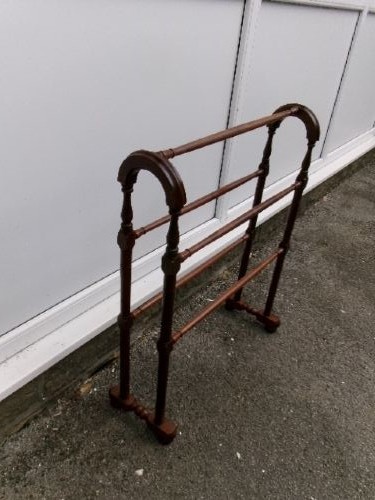 A freestanding Victorian mahogany towel rail featuring arched side supports, turned upright spindles, and four horizontal crossbars.