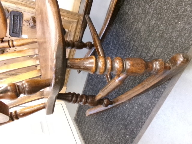 A Victorian dark oak rocking chair featuring a shaped crest rail, vertical spindles, turned arm supports, a solid wooden seat, and curved runners. View IV