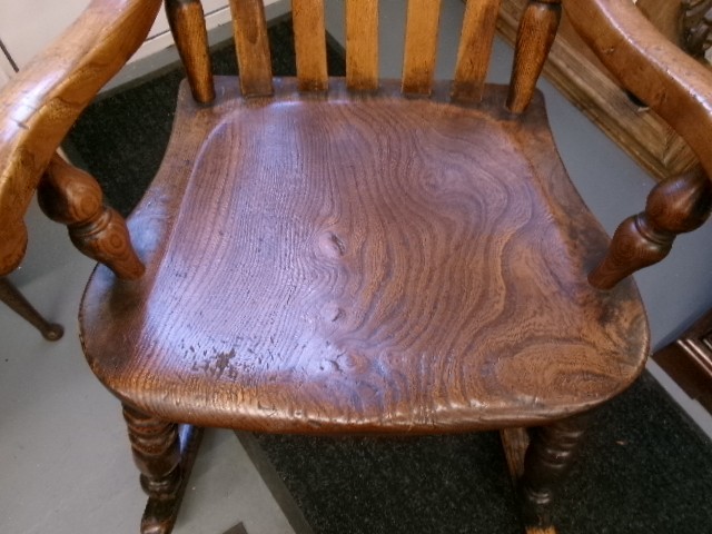 A Victorian dark oak rocking chair featuring a shaped crest rail, vertical spindles, turned arm supports, a solid wooden seat, and curved runners. View VIII
