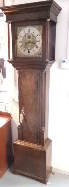 An 18th-century Georgian dark oak longcase clock featuring a square brass dial, fluted hood columns, and a moulded base.