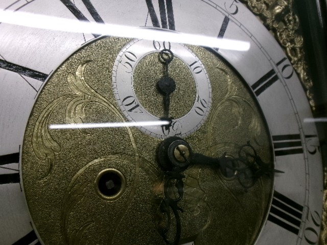 An 18th-century Georgian dark oak longcase clock featuring a square brass dial, fluted hood columns, and a moulded base. View V