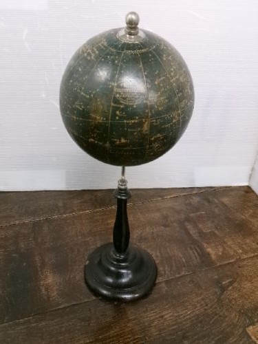 A 1930s celestial globe with a dark green sphere depicting printed constellations, supported on a turned ebonised black wooden stand with a metal axis.