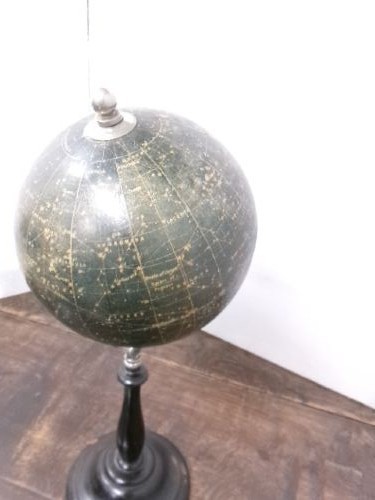 A 1930s celestial globe with a dark green sphere depicting printed constellations, supported on a turned ebonised black wooden stand with a metal axis. View III