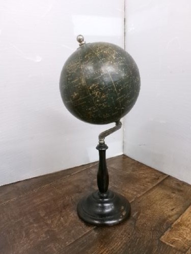 A 1930s celestial globe with a dark green sphere depicting printed constellations, supported on a turned ebonised black wooden stand with a metal axis. View VII