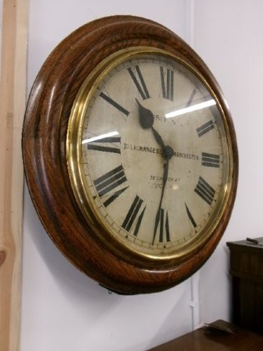 A circular antique wall clock housed in a thick moulded oak case with a glazed brass bezel and painted dial displaying Roman numerals. View II