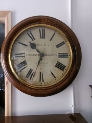 A circular antique wall clock housed in a thick moulded oak case with a glazed brass bezel and painted dial displaying Roman numerals. View V