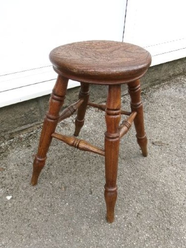 An antique Victorian wooden tavern stool featuring a circular thick elm seat and turned splayed legs joined by stretchers. View VI