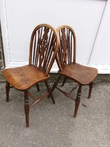 A pair of traditional wooden Windsor chairs featuring contoured elm seats, pierced wheelback splats, hoop backs, and turned legs connected by H-stretchers. View II