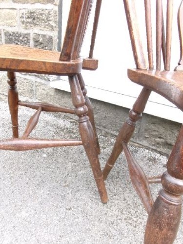 A pair of traditional wooden Windsor chairs featuring contoured elm seats, pierced wheelback splats, hoop backs, and turned legs connected by H-stretchers. View V