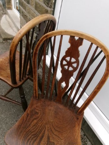 A pair of traditional wooden Windsor chairs featuring contoured elm seats, pierced wheelback splats, hoop backs, and turned legs connected by H-stretchers. View VI