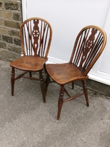 A pair of traditional wooden Windsor chairs featuring contoured elm seats, pierced wheelback splats, hoop backs, and turned legs connected by H-stretchers. View IX
