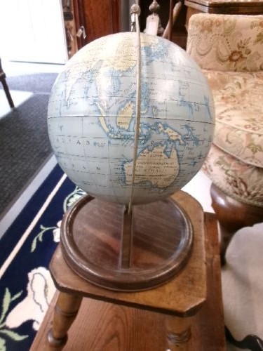 A vintage tinplate world globe with a pale blue lithographed ocean map mounted on a circular metal base with a curved semi-meridian arm. View IX