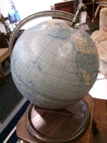 A vintage tinplate world globe with a pale blue lithographed ocean map mounted on a circular metal base with a curved semi-meridian arm. View X