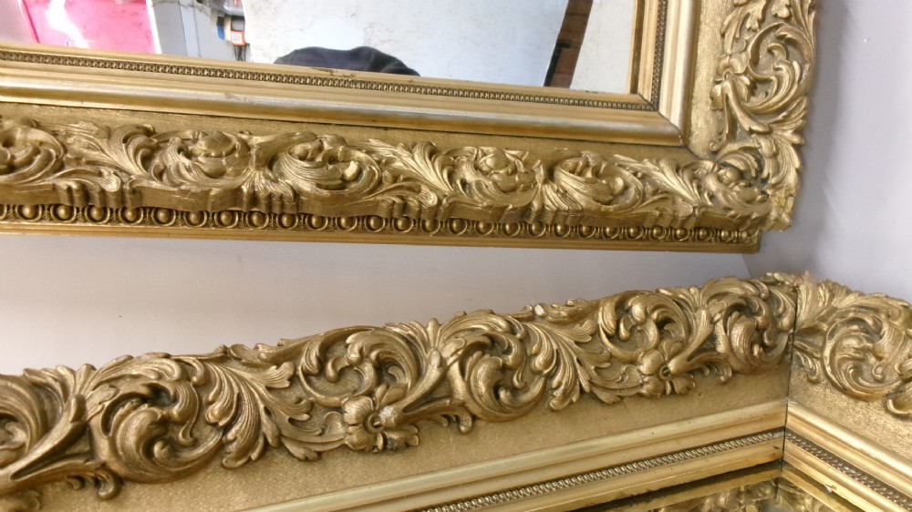A matching pair of rectangular wall mirrors featuring deeply carved gold gilt frames with ornate scrollwork and moulding. View II