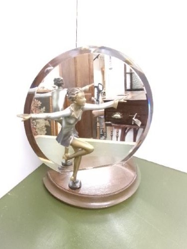 An Art Deco spelter figure of a dancing female posing dynamically in front of a circular bevelled glass mirror set on a wooden plinth base. View VII