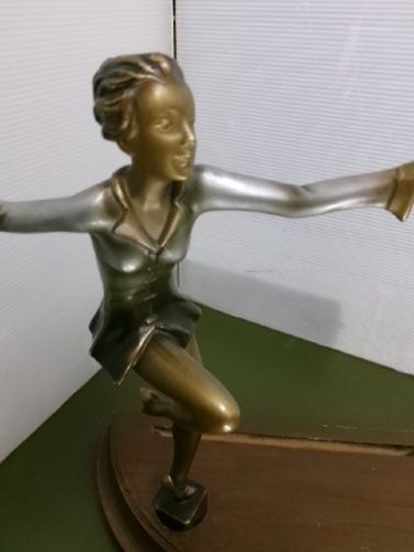 An Art Deco spelter figure of a dancing female posing dynamically in front of a circular bevelled glass mirror set on a wooden plinth base. View IX