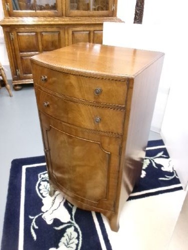 An Edwardian bow-front mahogany cabinet featuring two upper drawers with brass knobs over a panelled cupboard door. View III