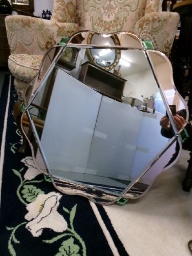 An Art Deco frameless wall mirror featuring peach-tinted geometric border panels, green corner clips, and a scalloped edge silhouette. View V