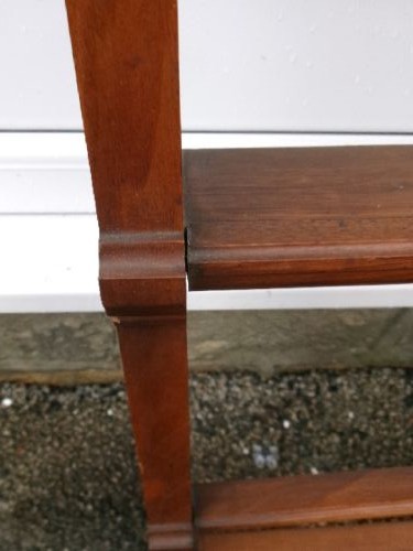 A mahogany wall-hanging rack featuring a top shelf, open tiers with horizontal retaining bars, shaped side brackets, and top brass mounting rings. View II