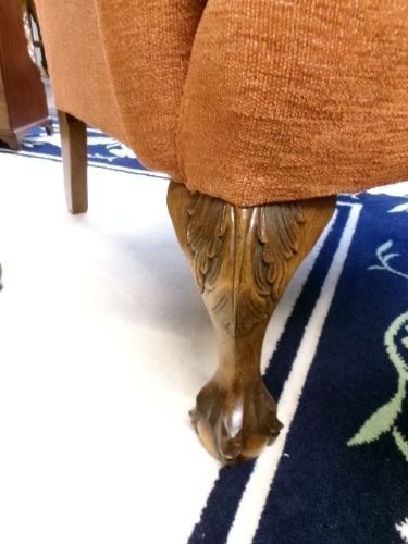A high-backed Georgian style wing armchair with rolled arms, upholstered in textured orange fabric, accompanied by a matching square footstool. View IV