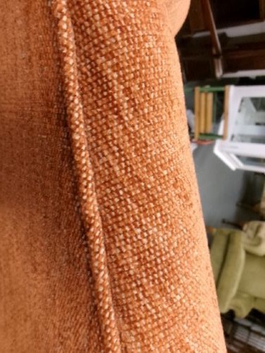 A high-backed Georgian style wing armchair with rolled arms, upholstered in textured orange fabric, accompanied by a matching square footstool. View VI