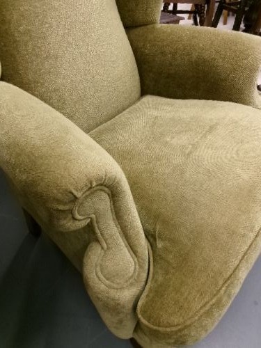 A high-backed Georgian style wing armchair upholstered in textured olive green fabric with dark wooden legs. View II