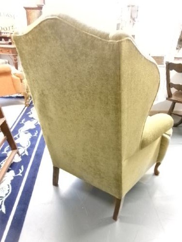 A high-backed Georgian style wing armchair upholstered in textured olive green fabric with dark wooden legs. View IV