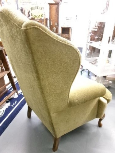 A high-backed Georgian style wing armchair upholstered in textured olive green fabric with dark wooden legs. View V