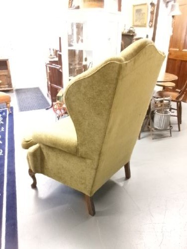 A high-backed Georgian style wing armchair upholstered in textured olive green fabric with dark wooden legs. View VI