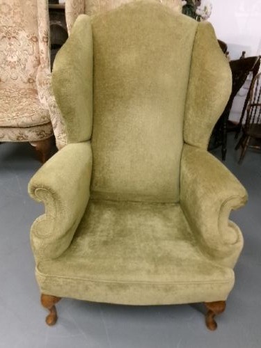 A high-backed Georgian style wing armchair upholstered in textured olive green fabric with dark wooden legs. View IX