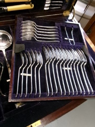 A dark mahogany freestanding cutlery cabinet with a open hinged lid displaying a fitted purple velvet interior with silver-plated flatware. View IX
