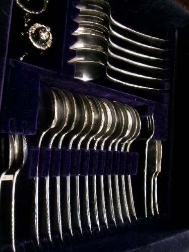 A dark mahogany freestanding cutlery cabinet with a open hinged lid displaying a fitted purple velvet interior with silver-plated flatware. View VIII