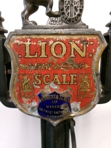 A Victorian cast iron and brass commercial weighing scale featuring a top lion crest, brass pan, and ceramic platform. View II