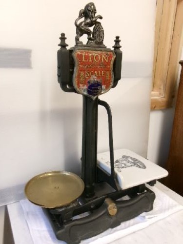 A Victorian cast iron and brass commercial weighing scale featuring a top lion crest, brass pan, and ceramic platform. View V