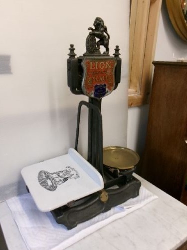 A Victorian cast iron and brass commercial weighing scale featuring a top lion crest, brass pan, and ceramic platform. View XII