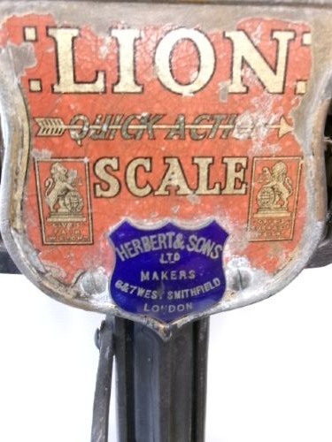 A Victorian cast iron and brass commercial weighing scale featuring a top lion crest, brass pan, and ceramic platform. View X