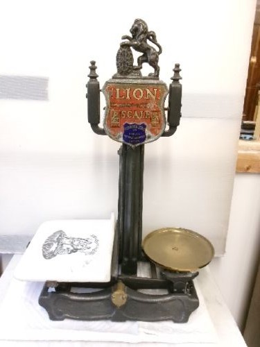 A Victorian cast iron and brass commercial weighing scale featuring a top lion crest, brass pan, and ceramic platform. View IX