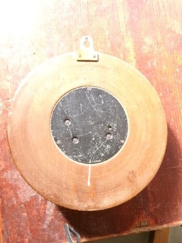 A circular Edwardian aneroid barometer set within a hand-carved mahogany frame with a brass bezel and visible mechanical movement. View VI
