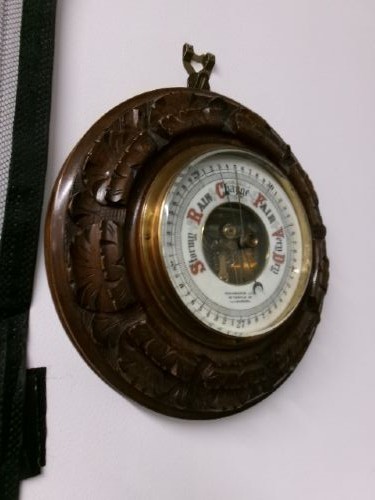 A circular Edwardian aneroid barometer set within a hand-carved mahogany frame with a brass bezel and visible mechanical movement. View VIII