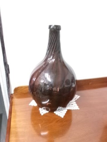 A deep amethyst hand-blown glass bottle featuring a bulbous onion-shaped body, a spiral-ribbed tapering neck, and an applied string lip rim. View VII