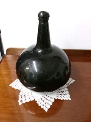 A dark green hand-blown glass onion bottle featuring a broad bulbous body, a long tapered neck, and an applied glass string rim.