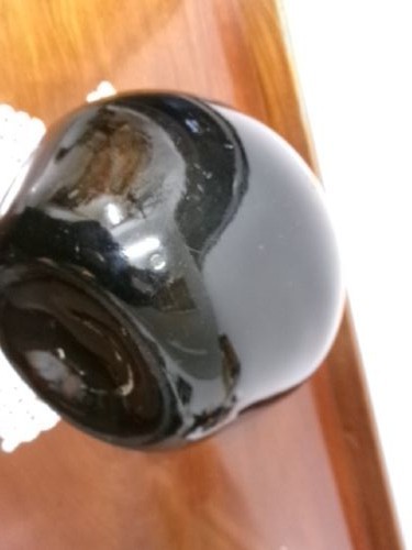 A dark green hand-blown glass onion bottle featuring a broad bulbous body, a long tapered neck, and an applied glass string rim. View V