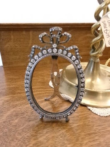 A small silver-plated oval easel picture frame decorated with clear paste stones and topped with a ribbon bow motif. View IV