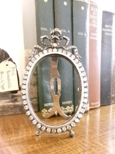 A small silver-plated oval easel picture frame decorated with clear paste stones and topped with a ribbon bow motif. View VII
