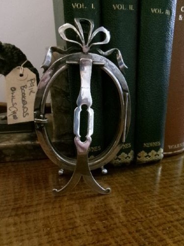 A small silver-plated oval easel picture frame decorated with clear paste stones and topped with a ribbon bow motif. View VIII