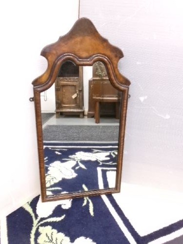 An antique walnut wall mirror with an arched, shaped top cresting and moulded frame. View VI