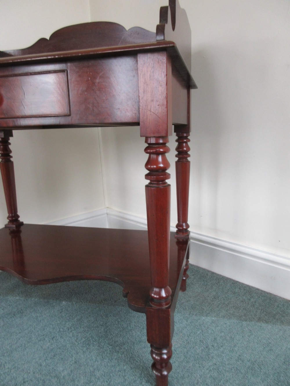 A Victorian mahogany night stand featuring a shaped gallery splashback, a single frieze drawer with a wooden knob, an open lower undertier, and turned legs. View II