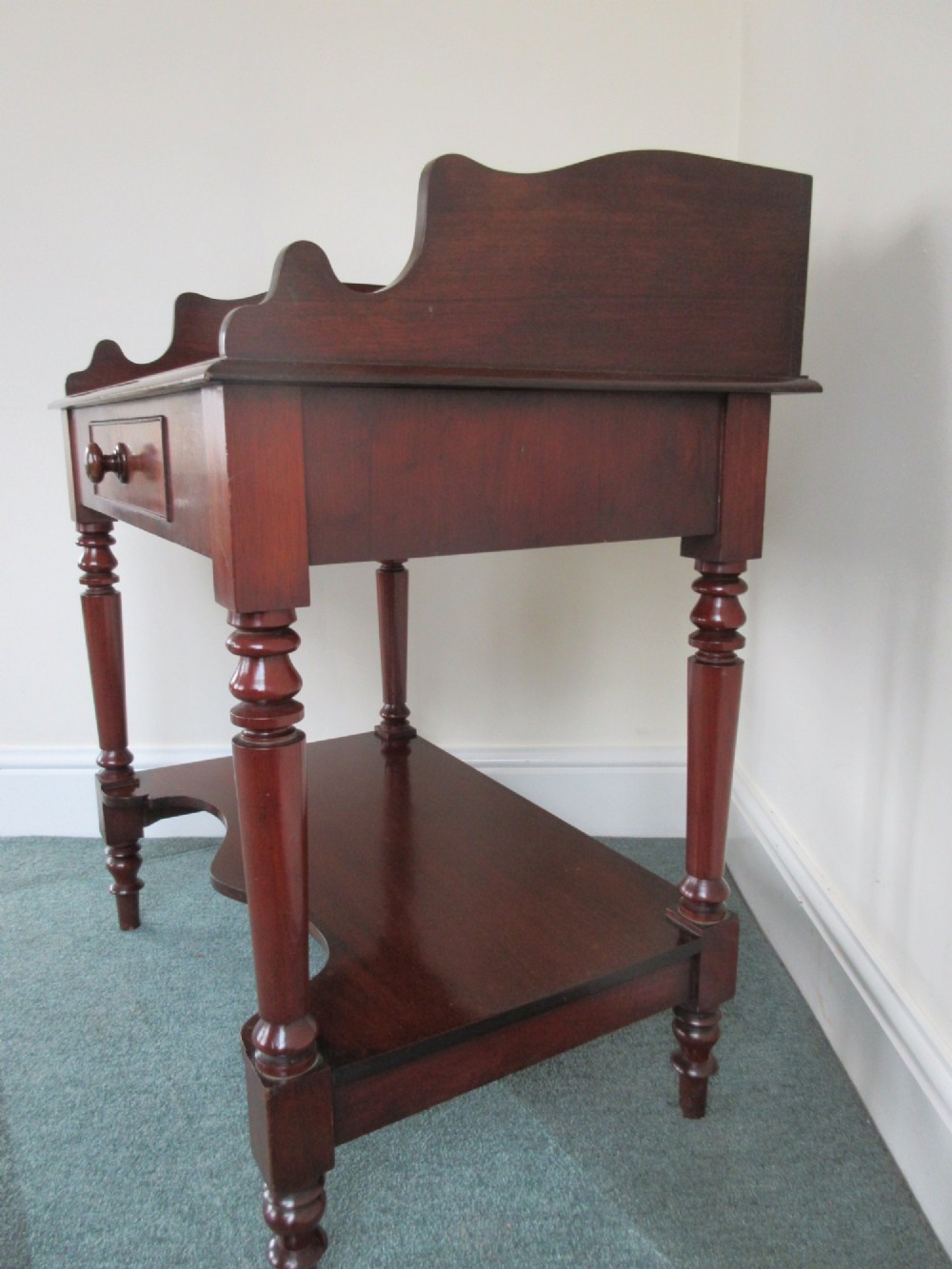 A Victorian mahogany night stand featuring a shaped gallery splashback, a single frieze drawer with a wooden knob, an open lower undertier, and turned legs. View III
