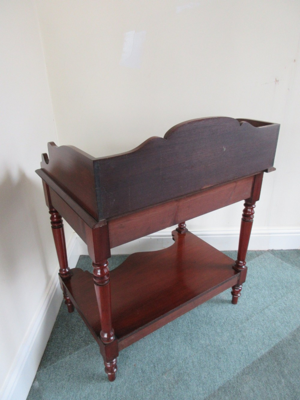 A Victorian mahogany night stand featuring a shaped gallery splashback, a single frieze drawer with a wooden knob, an open lower undertier, and turned legs. View IV