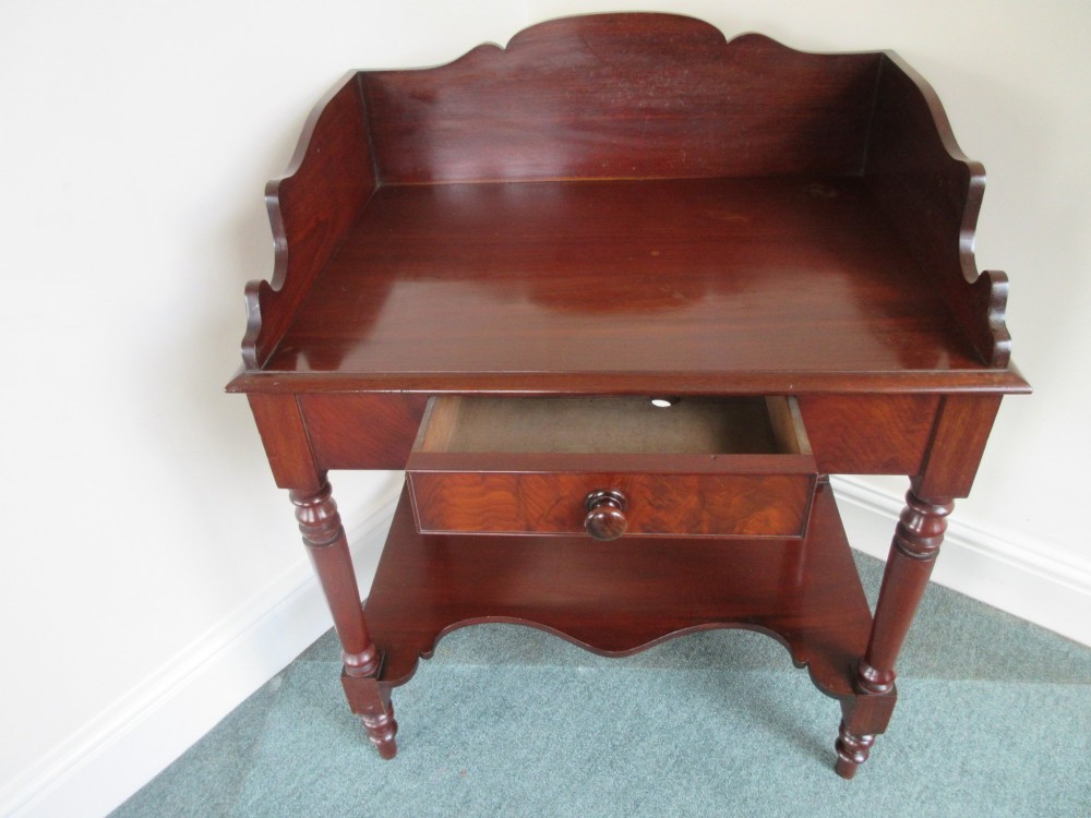 A Victorian mahogany night stand featuring a shaped gallery splashback, a single frieze drawer with a wooden knob, an open lower undertier, and turned legs. View V